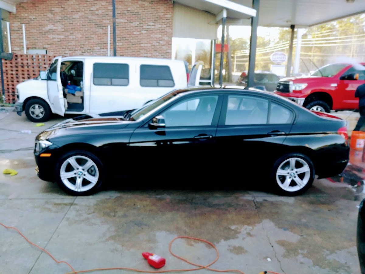 Black BMW sedan being detailed at the We Do It All Detail shop bay