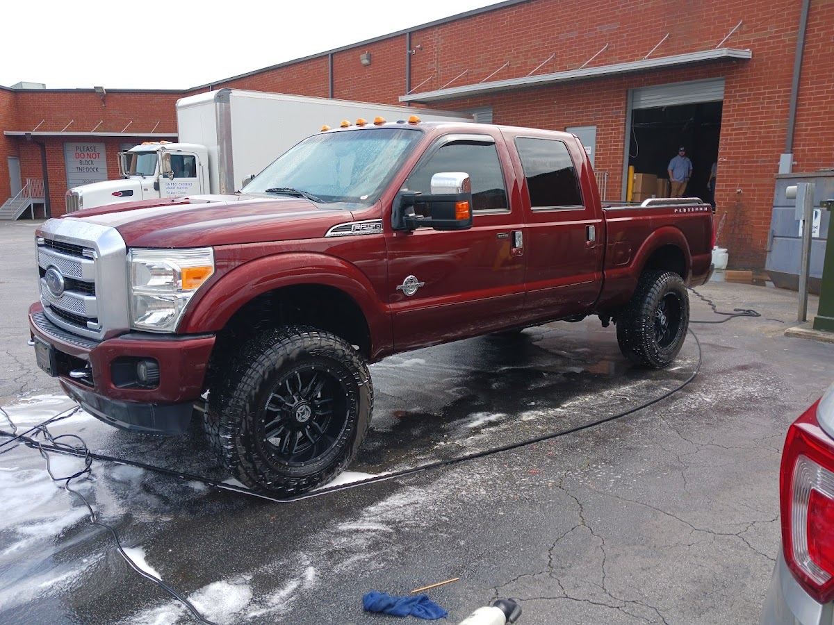 Maroon Ford F-250 lifted truck mid-wash at the detailing shop