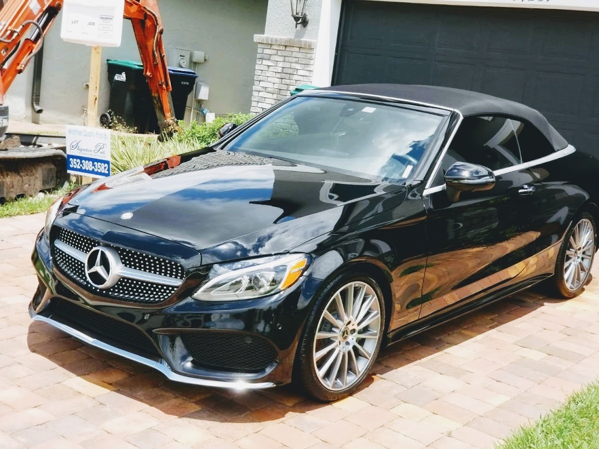 Black Mercedes convertible polished to a mirror shine on paver driveway