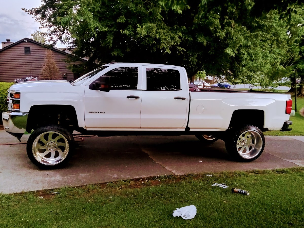 White Chevy Silverado lifted truck with chrome wheels, freshly detailed